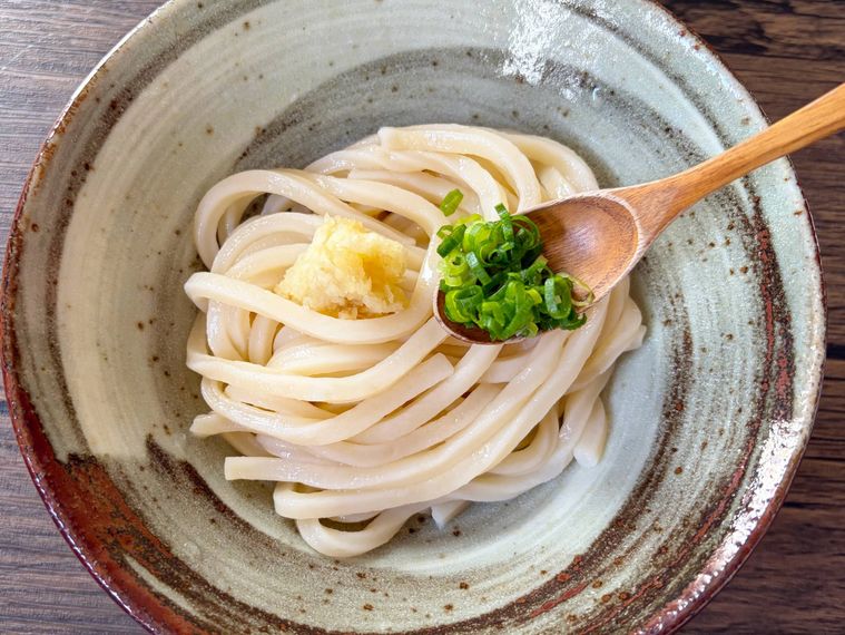 うどんに小口ねぎをのせる様子