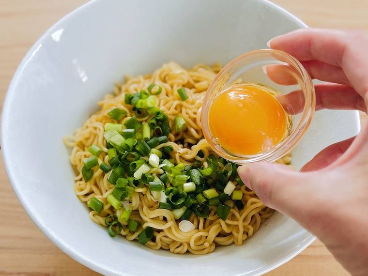 油そばに卵黄をトッピングしている様子