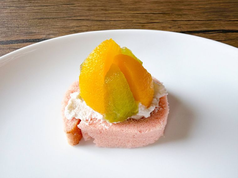ロールケーキの上に黄桃やキウイをおいた様子