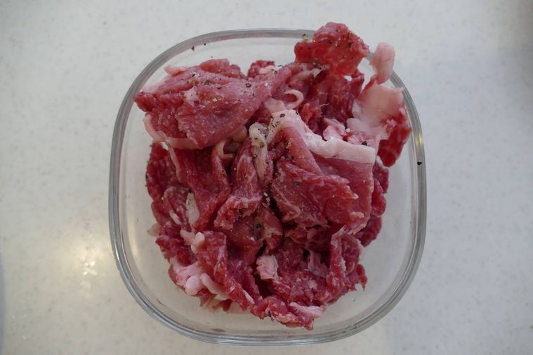 牛こま肉に塩と黒こしょうをまぶした様子